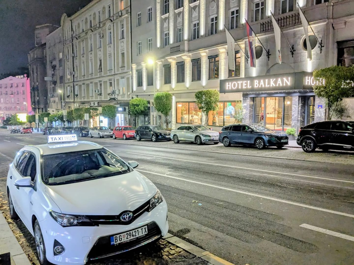 Beli Toyota Auris taxi ispred Hotela Balkan u centru Beograda noću